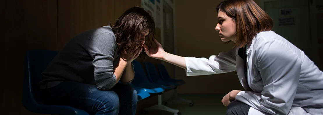 Врач протягивает руку помощи склонившемуся пациенту.